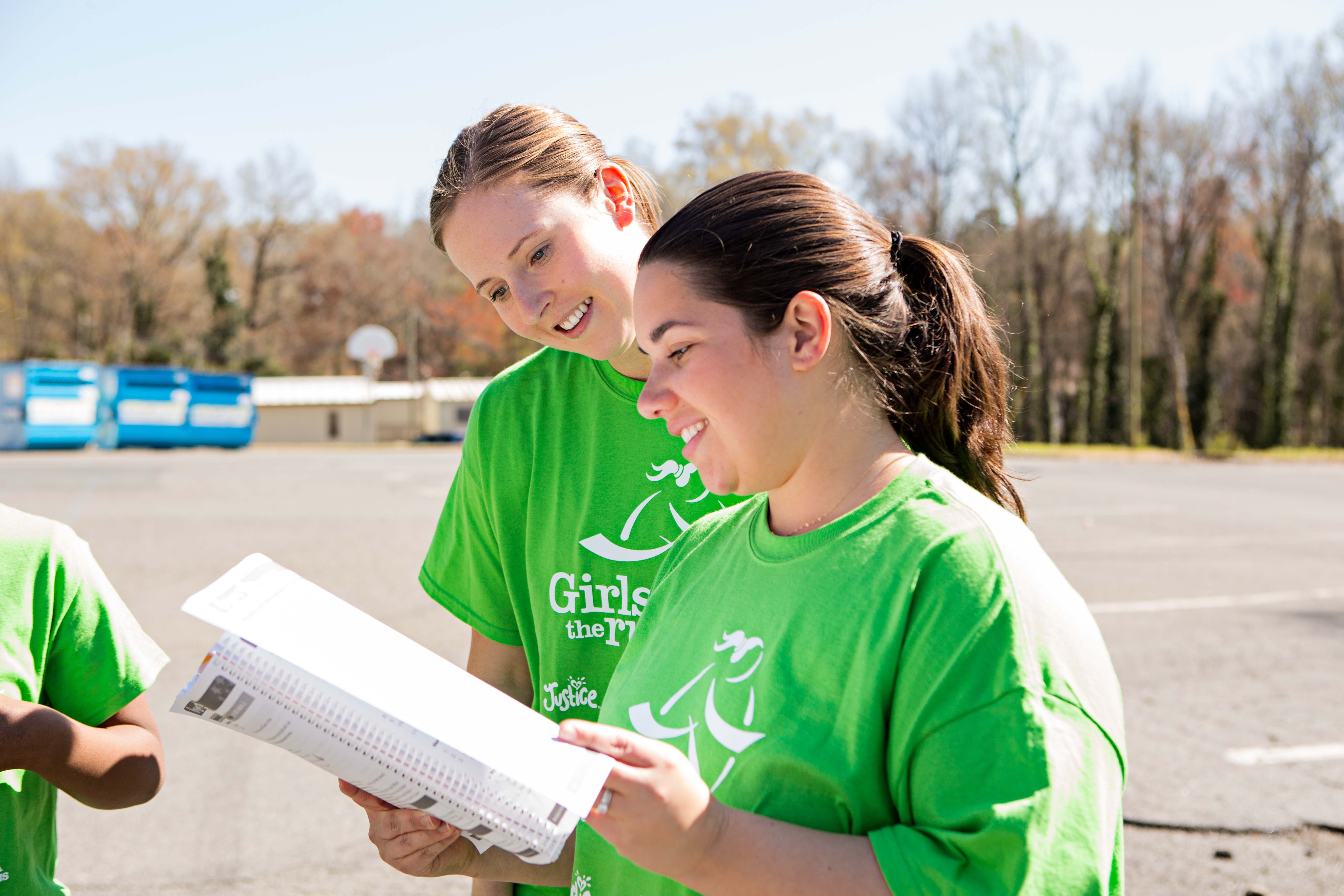 Smiling Girls on the Run Coach holding curriculum books